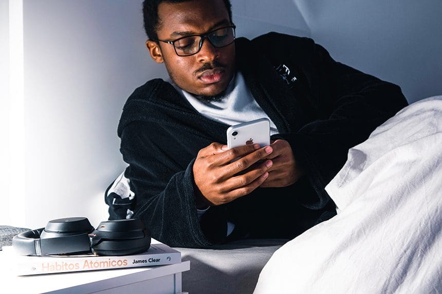 Man using an iPhone in bed.