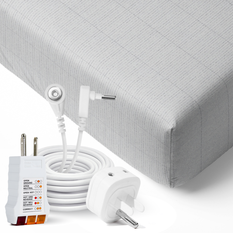 White and gray EMF protection charging cables and wall adapters with electrical plugs, neatly arranged on a light gray fabric background