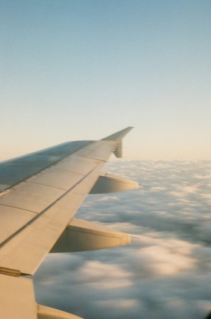 View from airplane window showing wing and clouds during flight