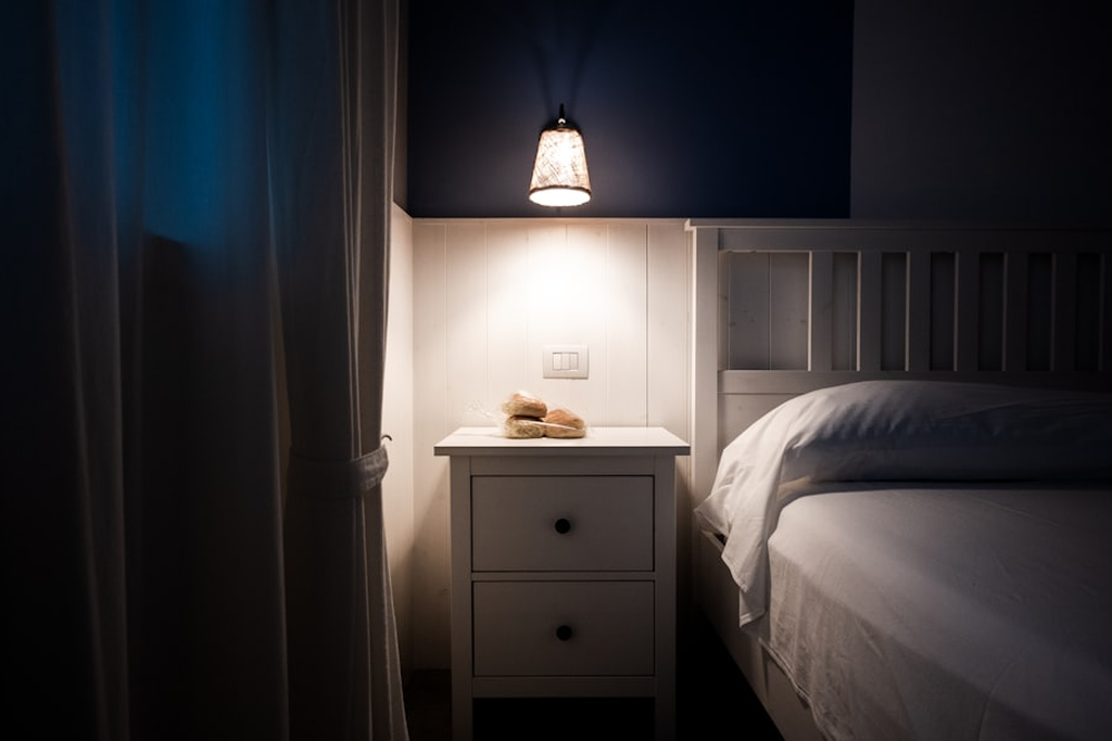 Smartphone glowing on a wooden bedside table at night, illustrating a high-exposure habit no case mitigates